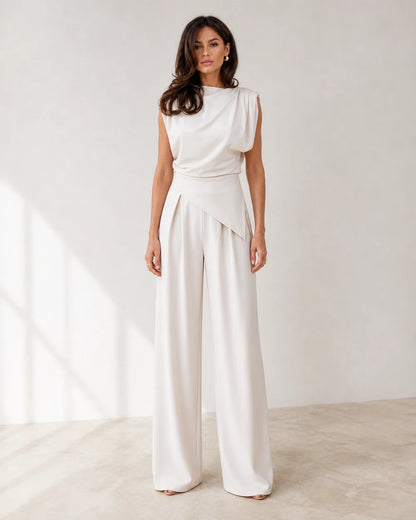 Women's white asymmetric draped top and wide-leg trousers set, full silhouette.