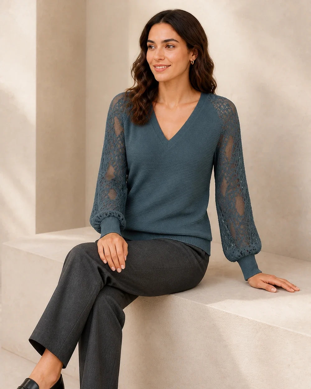 Women's Storm Blue ribbed V-neck sweater with floral lace sleeves, seated styling view.